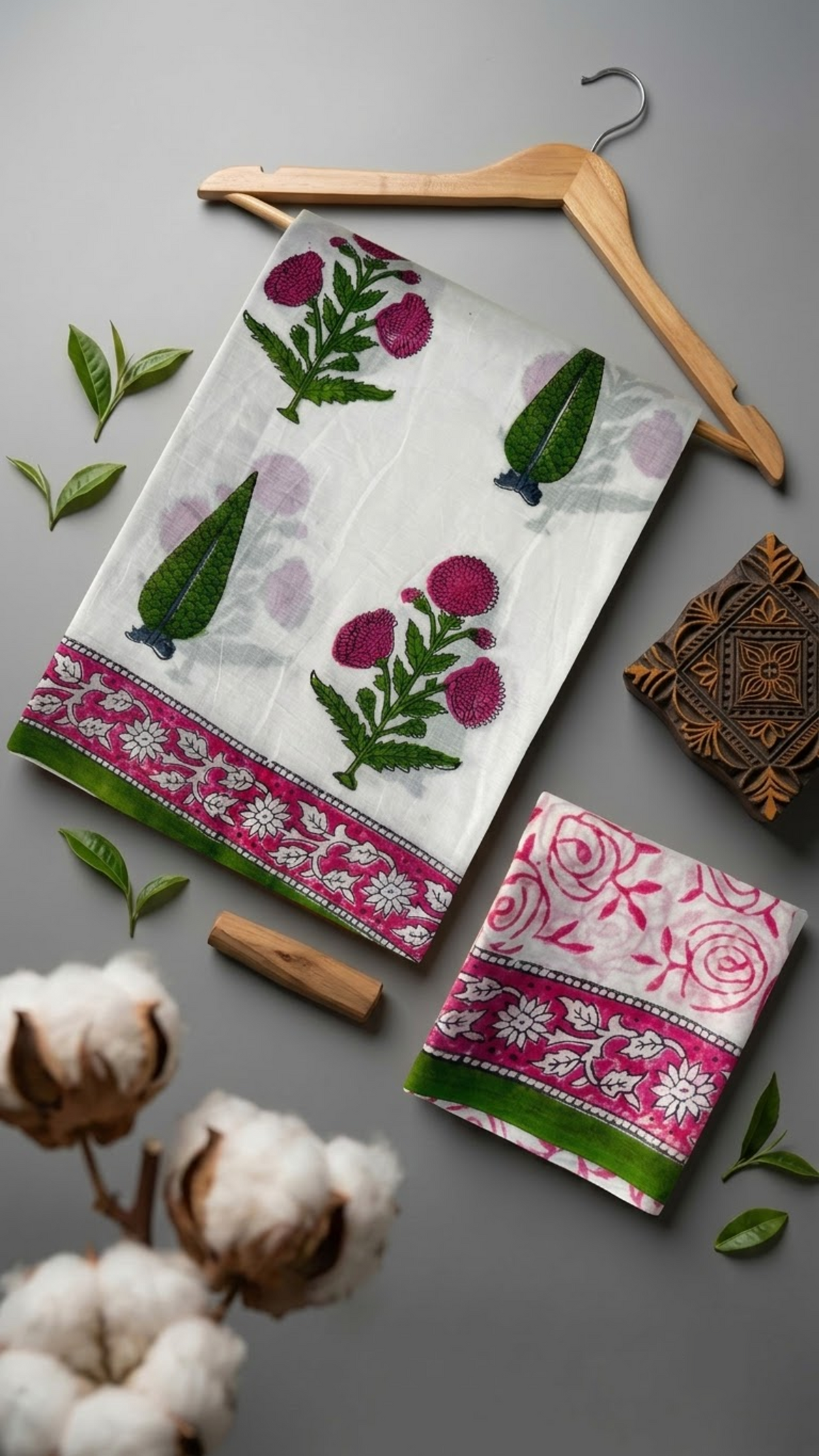 Ivory cotton saree with pink blossoms, green leafy sprigs, pink border, and ivory pink floral blouse piece, arranged with the blouse piece in a styled flat lay
