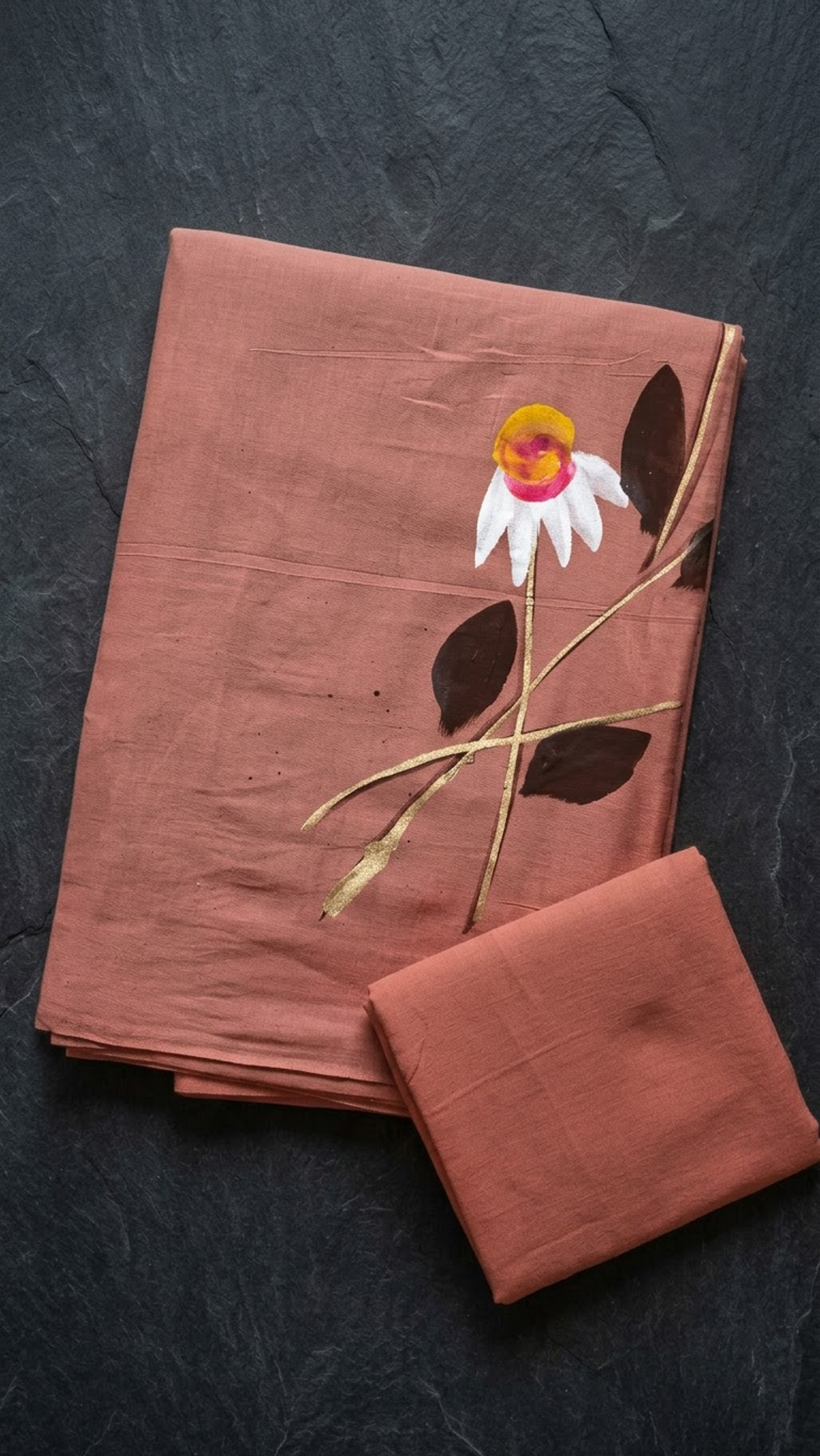 Dusty peach cotton saree with an ivory flower and dark leaves, folded on charcoal
