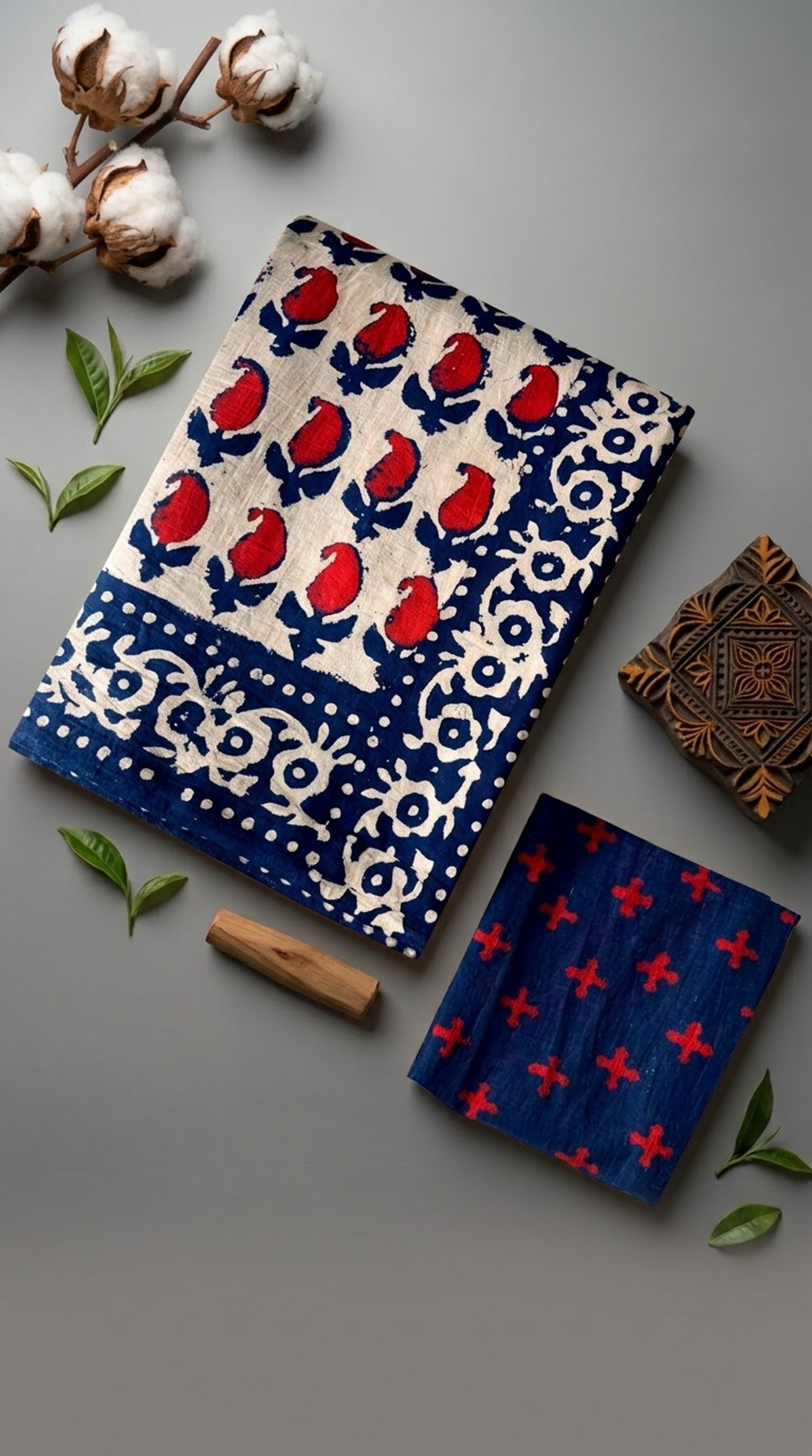 Ivory red bud print cotton saree with its navy floral border and navy red-cross blouse piece arranged in an artisan flat lay
