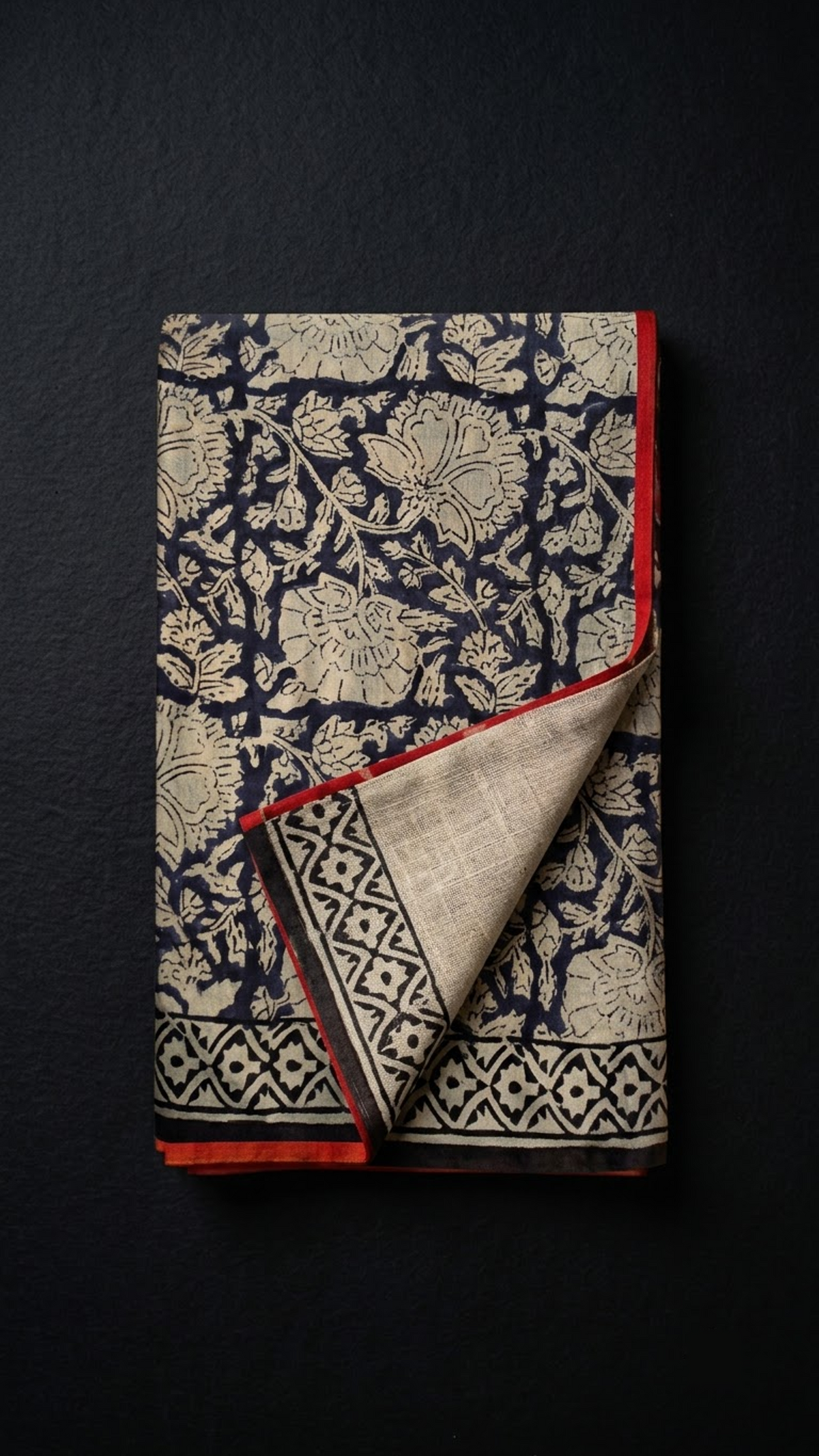 Folded dark floral vine cotton saree with blouse piece on a charcoal background