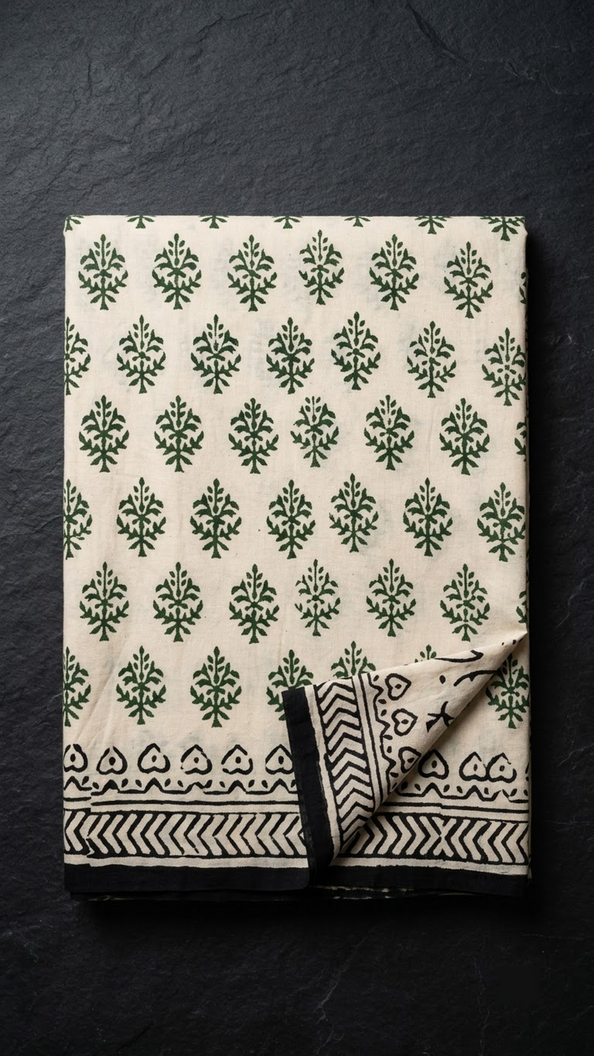 Folded ivory green botanical cotton saree with blouse piece on a charcoal background