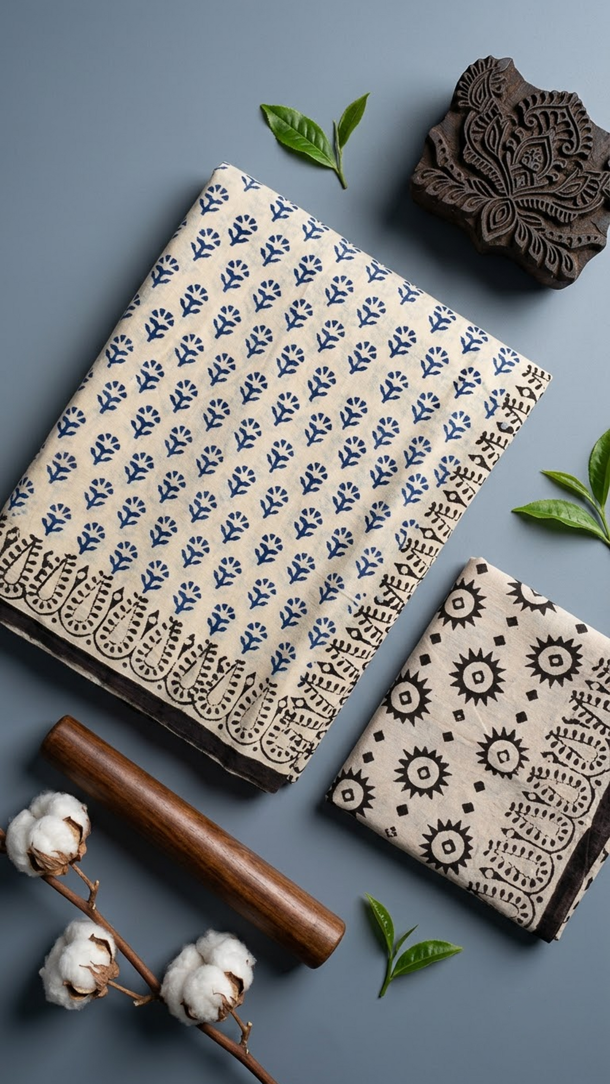 Ivory cotton saree with navy botanical sprigs, a black botanical loop border, and an ivory blouse piece with black starburst and diamond motifs, shown with the blouse piece in a close detail view