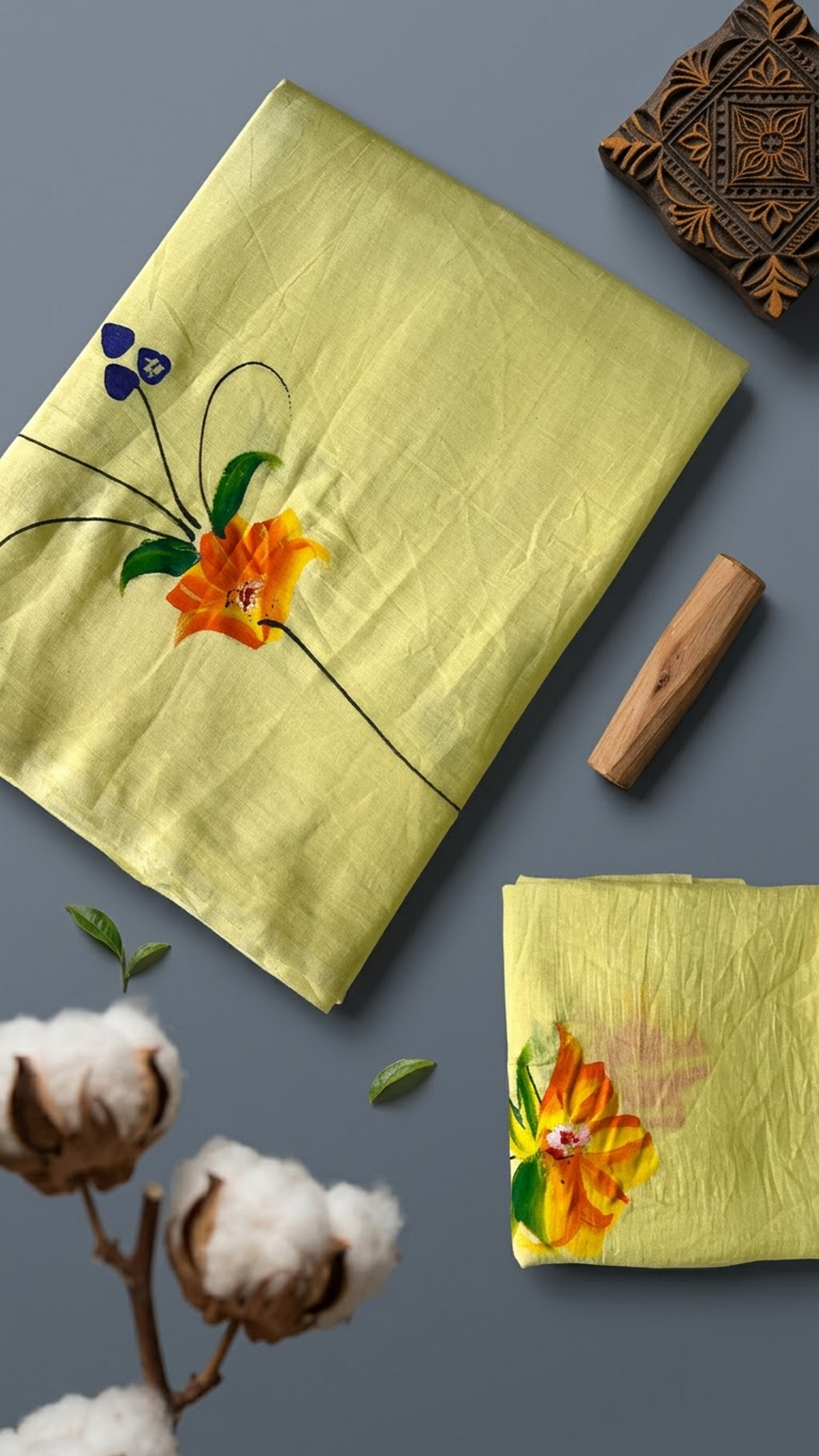 Lemon yellow cotton saree with an orange-yellow flower, green leaves, purple accents, and a coordinating floral blouse piece, shown with the blouse piece in a close detail view